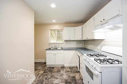 A kitchen with a white stove and cabinets.