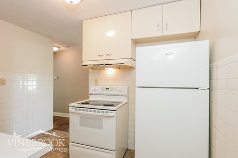 A white fridge and stove in a small kitchen.