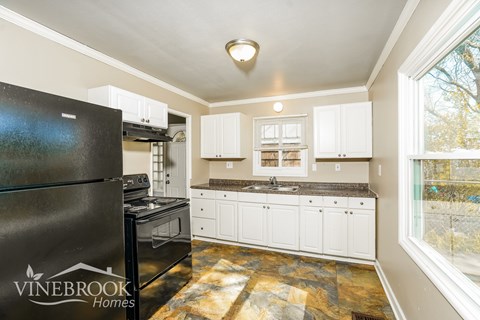 A kitchen with a black fridge and white cabinets.
