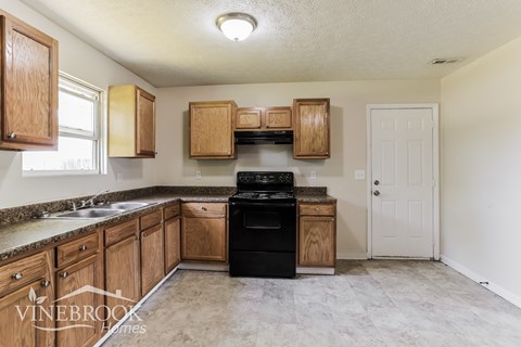 A kitchen with wooden cabinets and a black stove top oven.