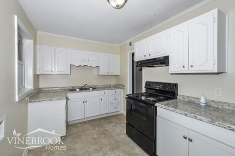 A kitchen with white cabinets and a black stove top oven.
