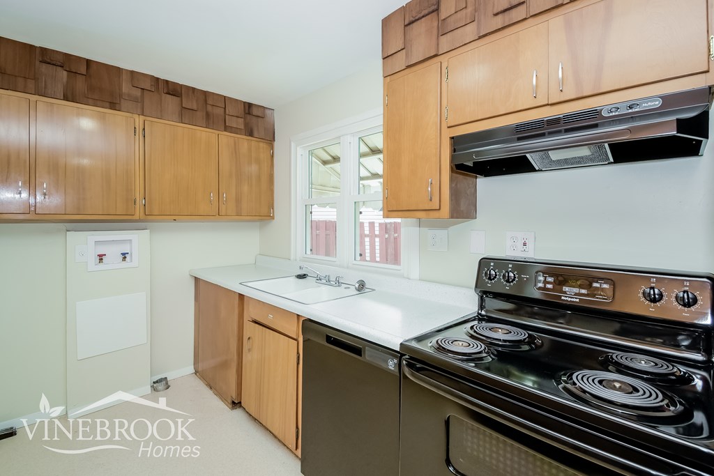 A kitchen with wooden cabinets and a black stove top oven.