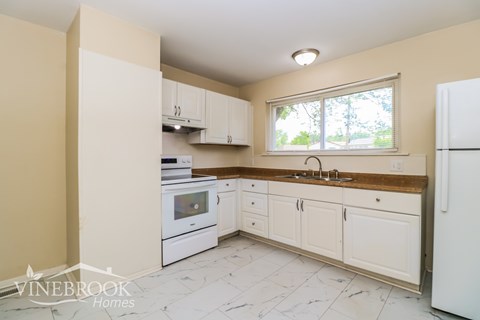 A kitchen with white appliances and cabinets.