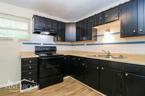 A kitchen with black cabinets and a black stove top oven.
