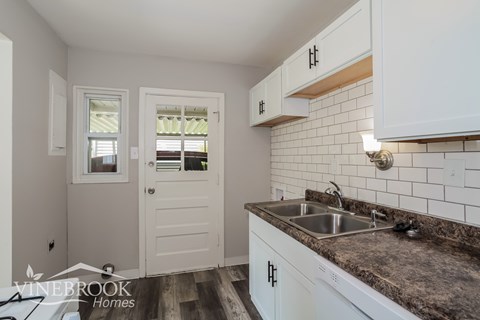 A kitchen with white cabinets and a sink.