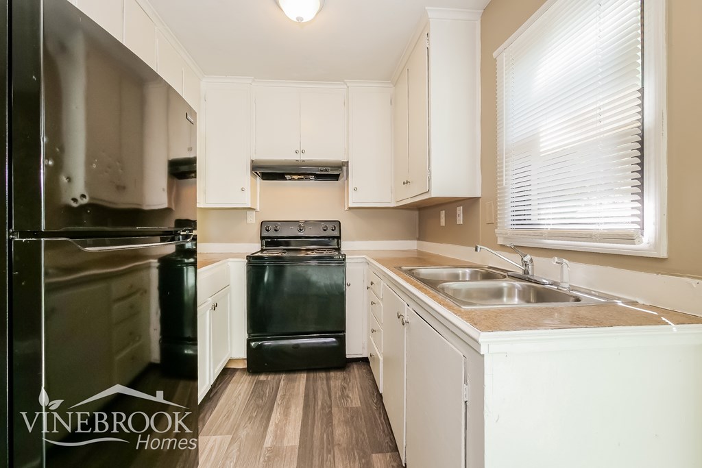 A kitchen with white cabinets and a black stove top oven.