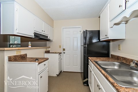 A kitchen with a black refrigerator and white cabinets.