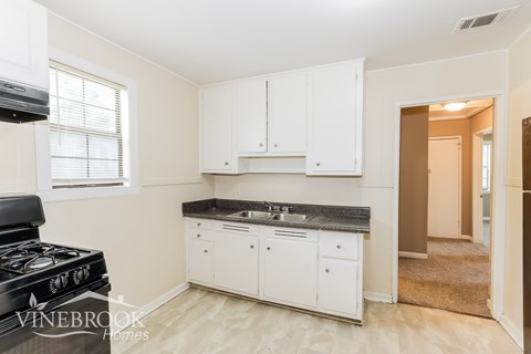 A kitchen with white cabinets and a black stove top.