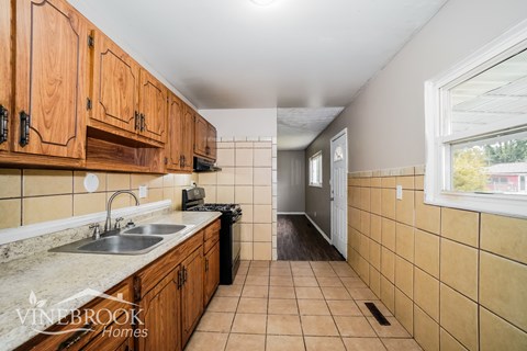 A kitchen with wooden cabinets and a tiled floor.