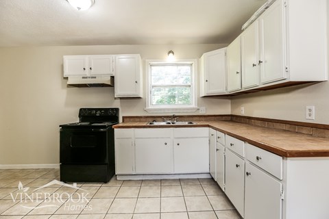 A kitchen with white cabinets and a black oven.