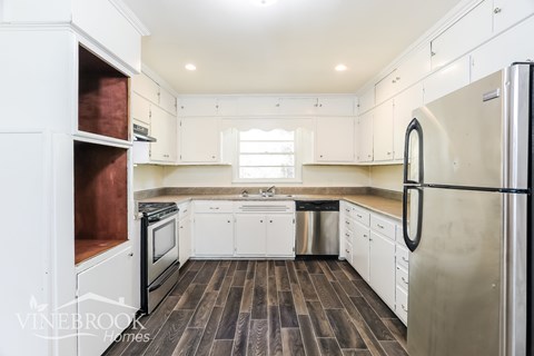 A kitchen with white cabinets and a stainless steel refrigerator.