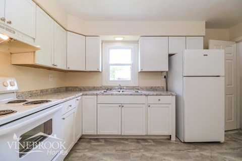 A kitchen with white cabinets and a white refrigerator.