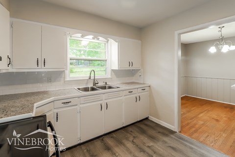A kitchen with white cabinets and a sink is shown.