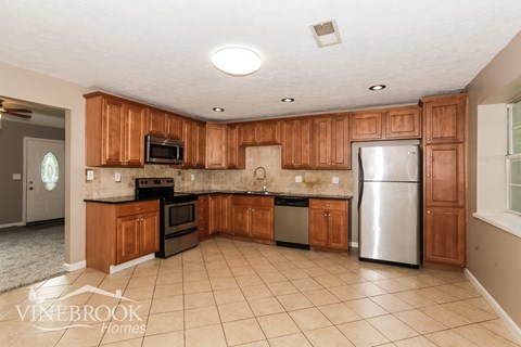 A kitchen with wooden cabinets and a refrigerator.