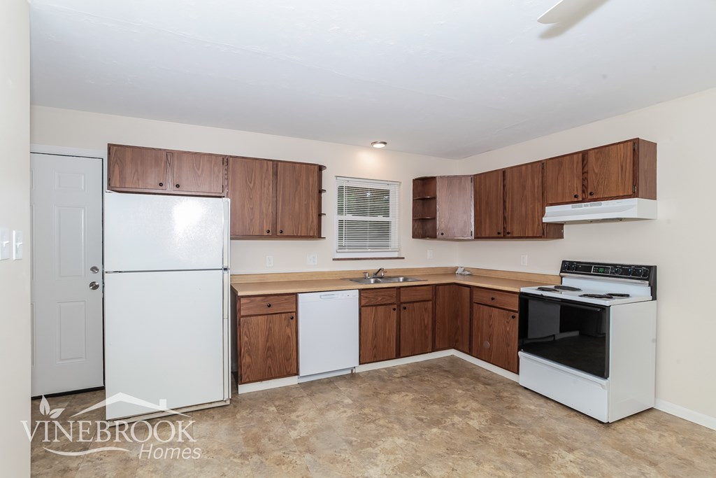 A kitchen with white appliances and brown cabinets.