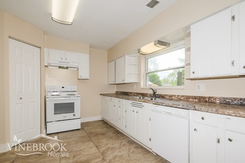 A kitchen with white cabinets and a stove top oven.