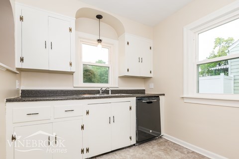 A kitchen with white cabinets and a black dishwasher.