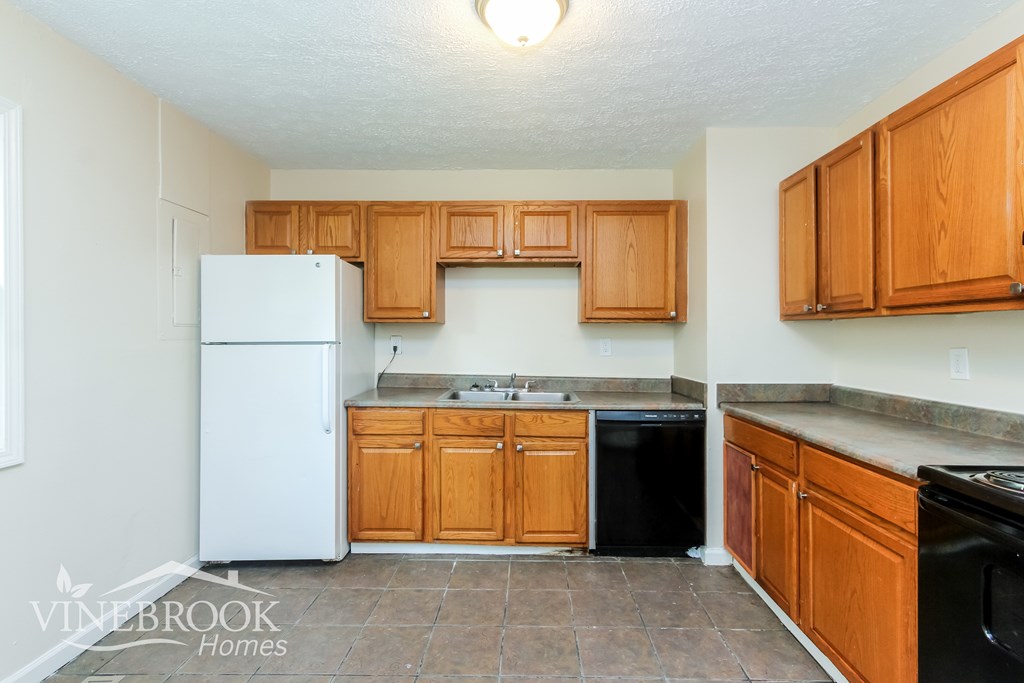 A kitchen with a white fridge and wooden cabinets.