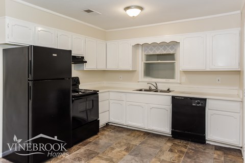 A kitchen with black appliances and white cabinets.