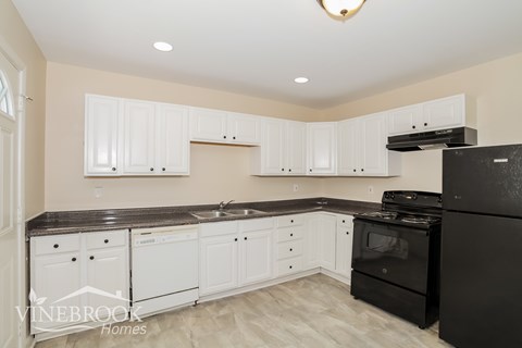 A kitchen with black appliances and white cabinets.