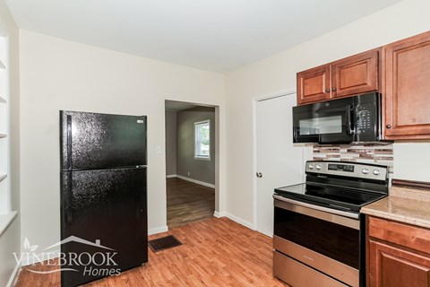 A kitchen with a black fridge, black microwave, and a black stove top oven.