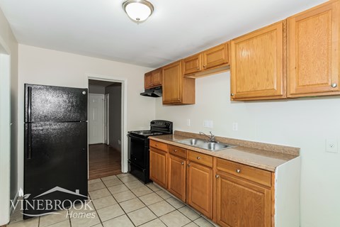 A kitchen with wooden cabinets and a black fridge.