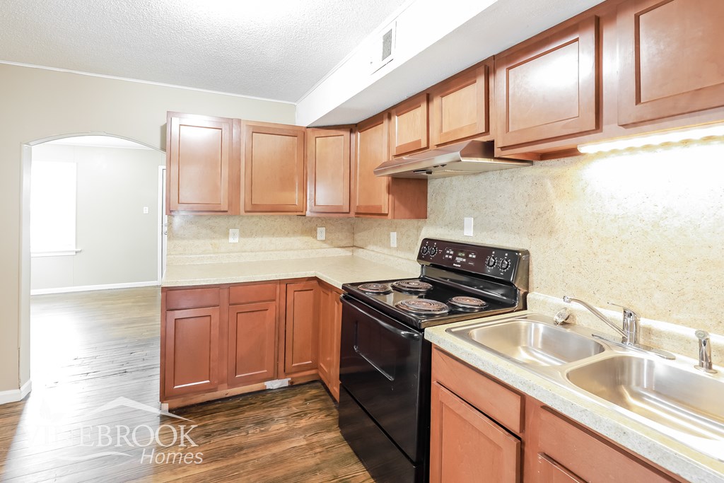 A kitchen with wooden cabinets and a black stove top oven.