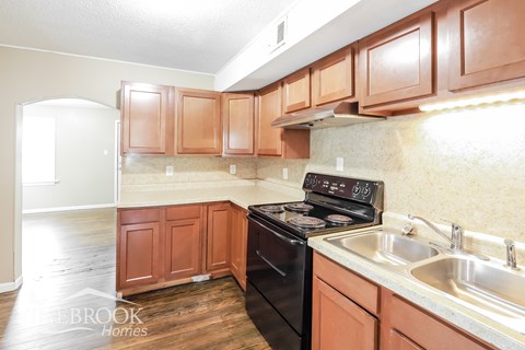 A kitchen with wooden cabinets and a black stove top oven.