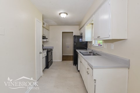 A kitchen with white cabinets and a black refrigerator.
