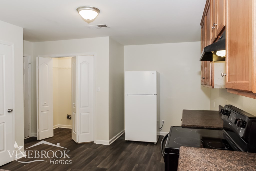 A kitchen with a refrigerator and stove top oven.