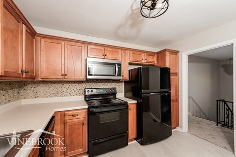 A kitchen with wooden cabinets and black appliances.