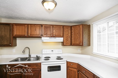 A kitchen with wooden cabinets and a white stove top oven.