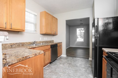 A kitchen with granite countertops and wooden cabinets.