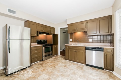 A kitchen with brown cabinets and a white fridge.