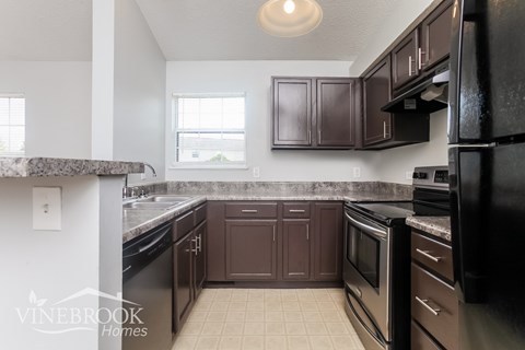 A kitchen with black appliances and brown cabinets.
