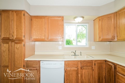A kitchen with wooden cabinets and a white dishwasher.