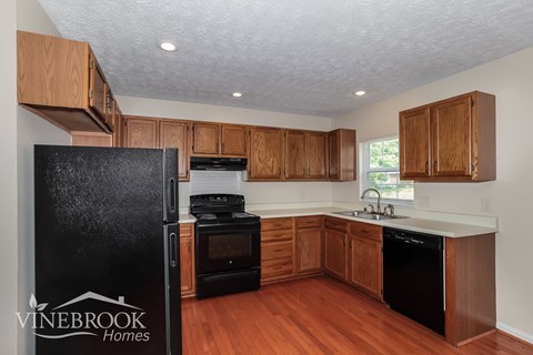 A kitchen with wooden cabinets and black appliances.