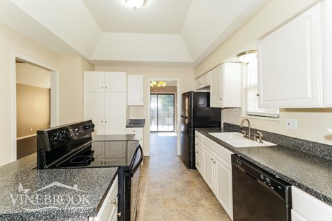 A kitchen with black appliances and white cabinets.