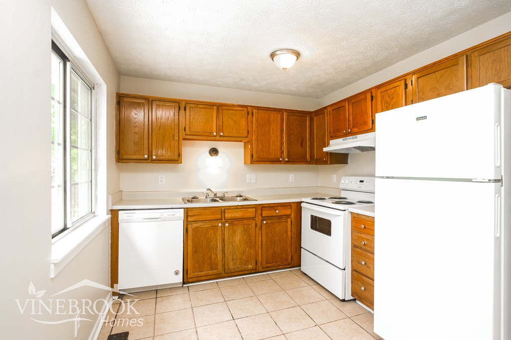 A kitchen with wooden cabinets and white appliances.