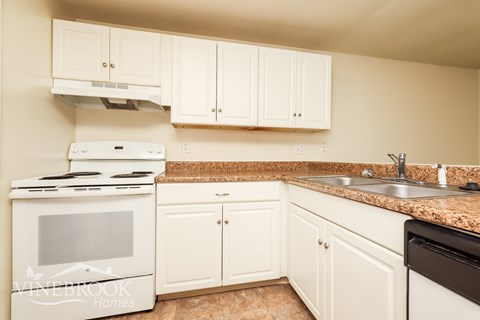 A kitchen with a white stove and cabinets.