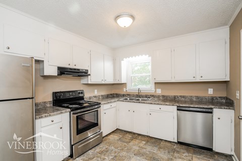 A kitchen with white cabinets and a granite countertop.