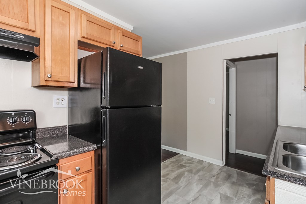 A kitchen with black appliances and wooden cabinets.