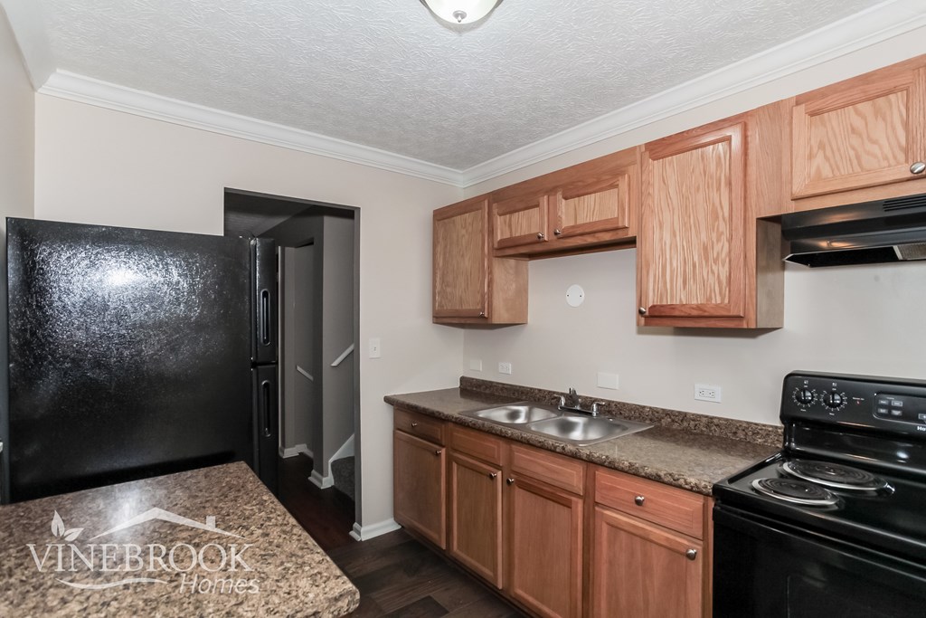 A kitchen with black appliances and wooden cabinets.