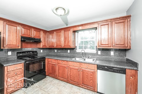 A kitchen with wooden cabinets and a black countertop.