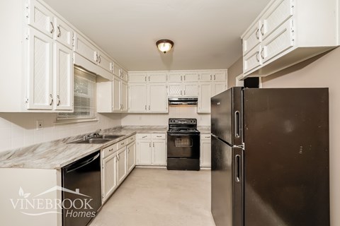 A kitchen with a black refrigerator and white cabinets.