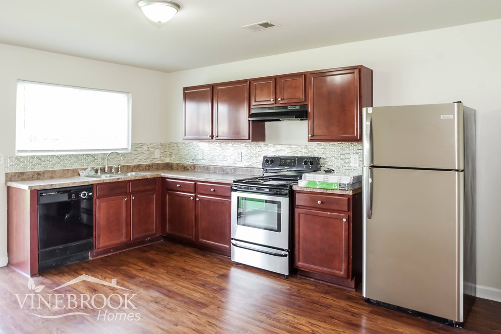 A kitchen with wooden cabinets and a stainless steel refrigerator.