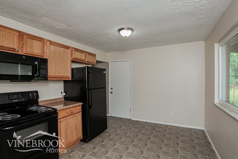 A kitchen with black appliances and wooden cabinets.