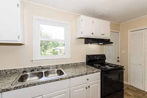 A kitchen with a black stove top oven and a window.