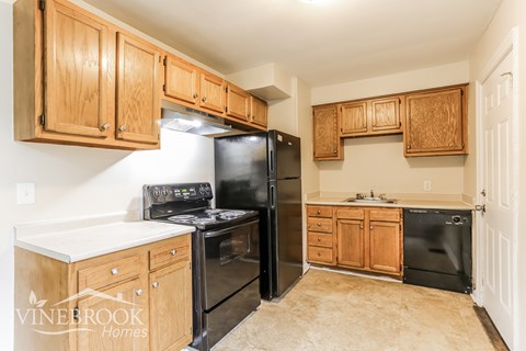 A kitchen with wooden cabinets and black appliances.