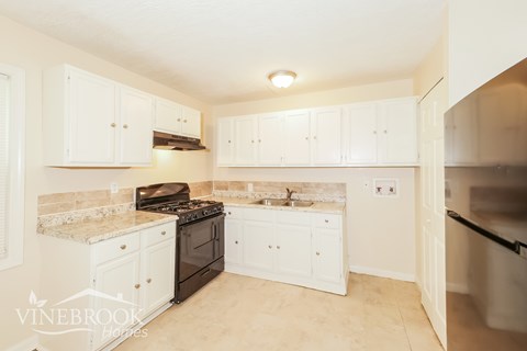 A kitchen with white cabinets and a black stove top.